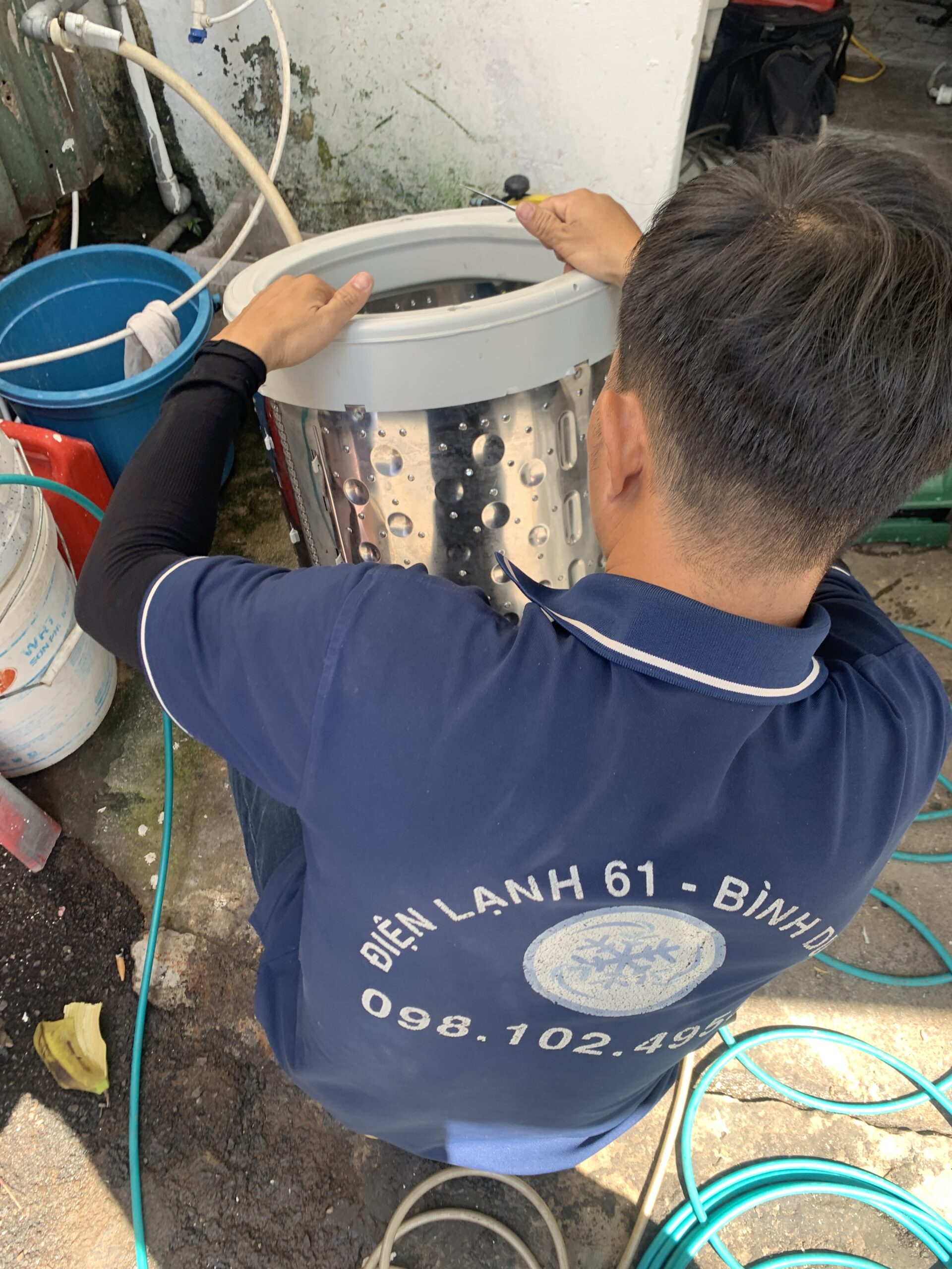 Dùng máy bơm áp lực cao xịt rửa sạch sẽ cặn bẩn, rong rêu bám dưới đáy lồng giặt.