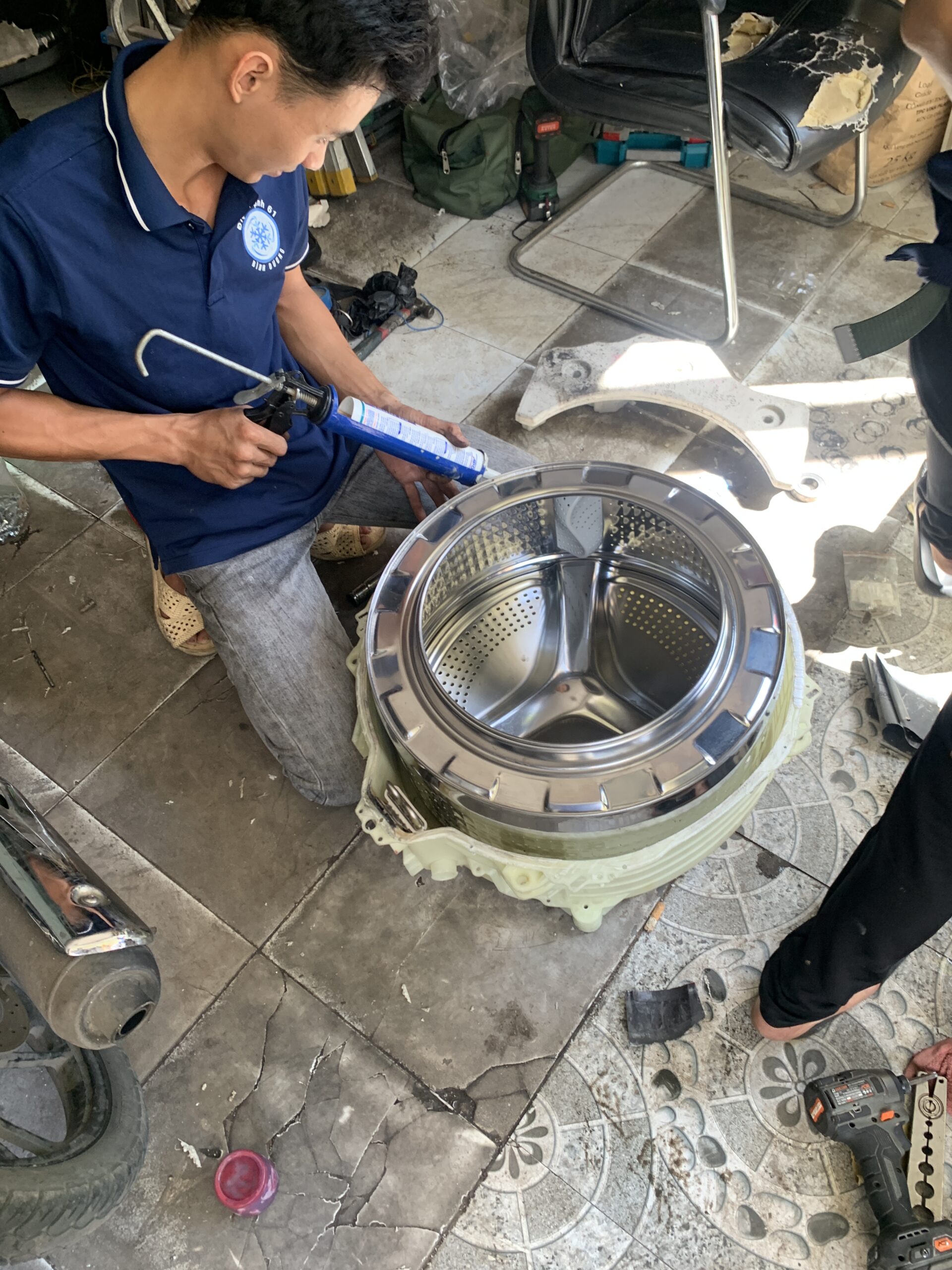 Kỹ thuật viên Điện Lạnh 61 nhấc lồng inox máy giặt ra khỏi vỏ để vệ sinh mặt ngoài.