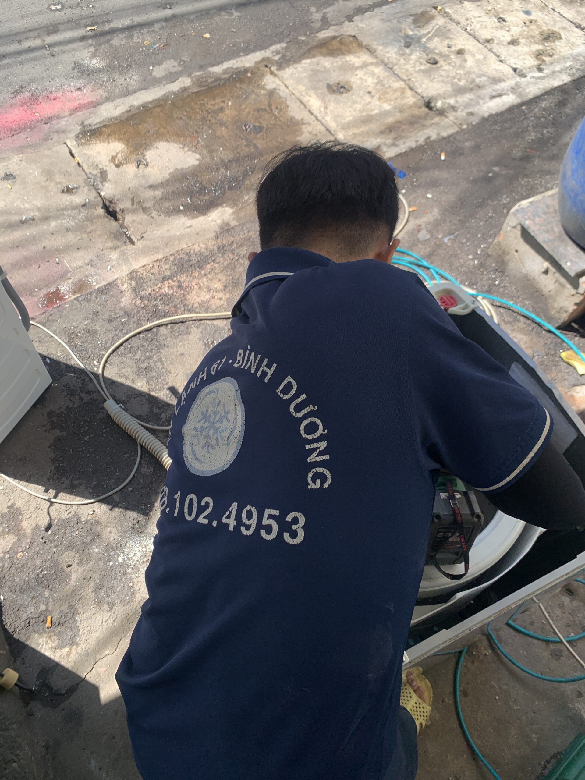 Kỹ thuật viên dùng máy bơm áp lực cao xịt rửa sạch sẽ lồng inox máy giặt.