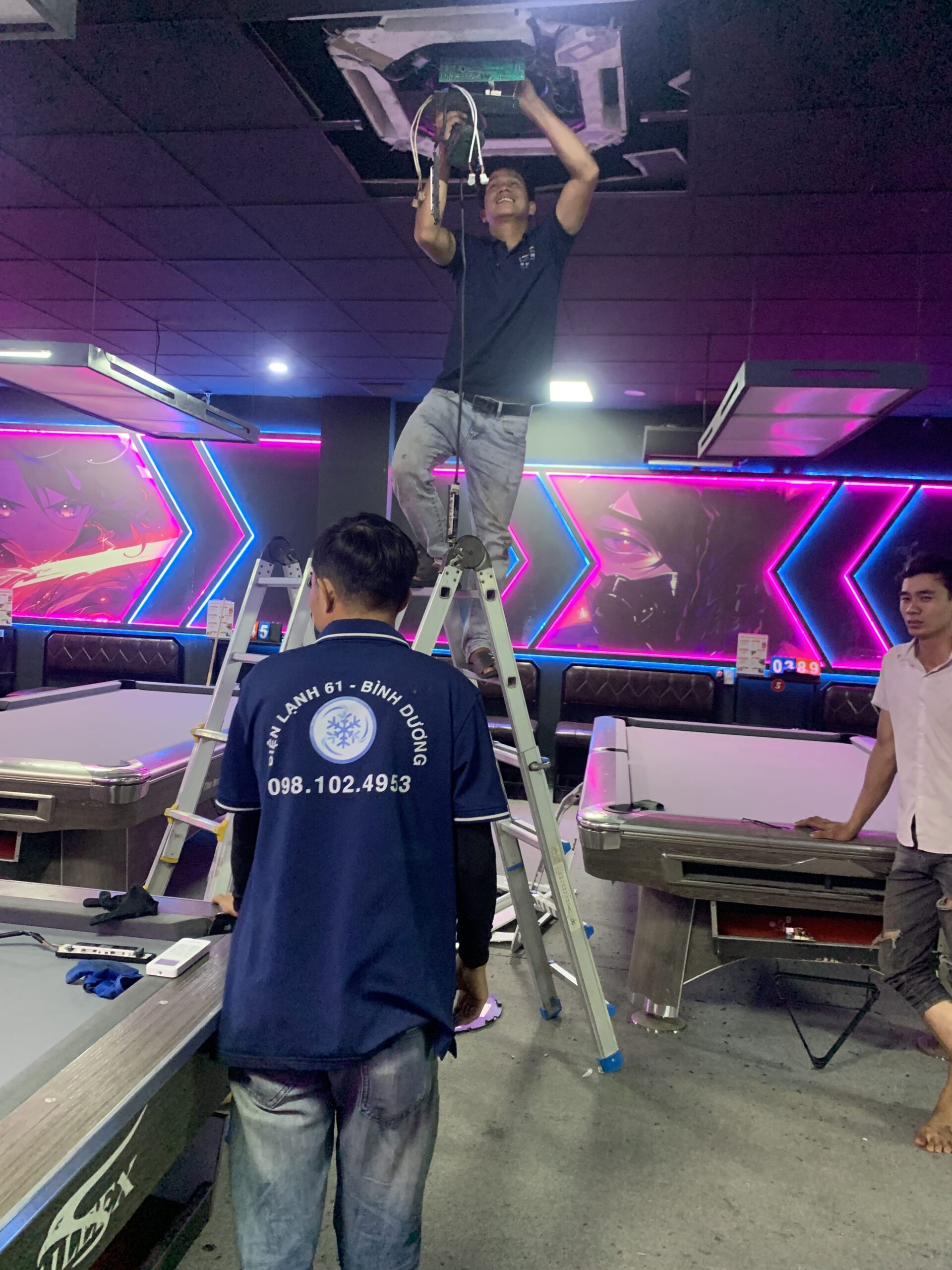 Thợ rửa máy lạnh tại Phường Dĩ An cẩn thận che chắn bo mạch điện tử trước khi xịt nước.