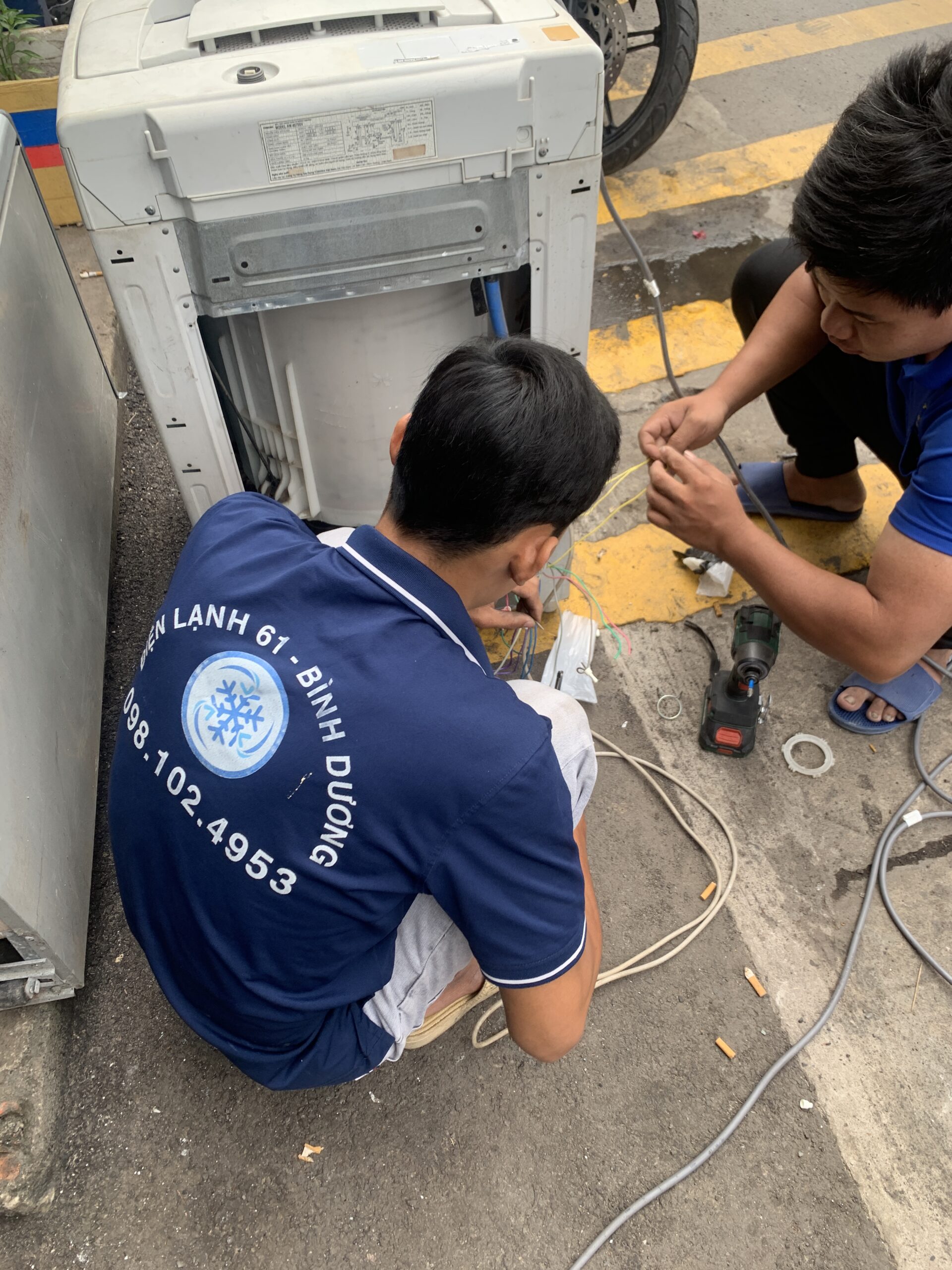 Thợ vệ sinh máy giặt Dĩ An của Điện Lạnh 61 dùng cảo chuyên dụng tháo lồng giặt cửa trên.