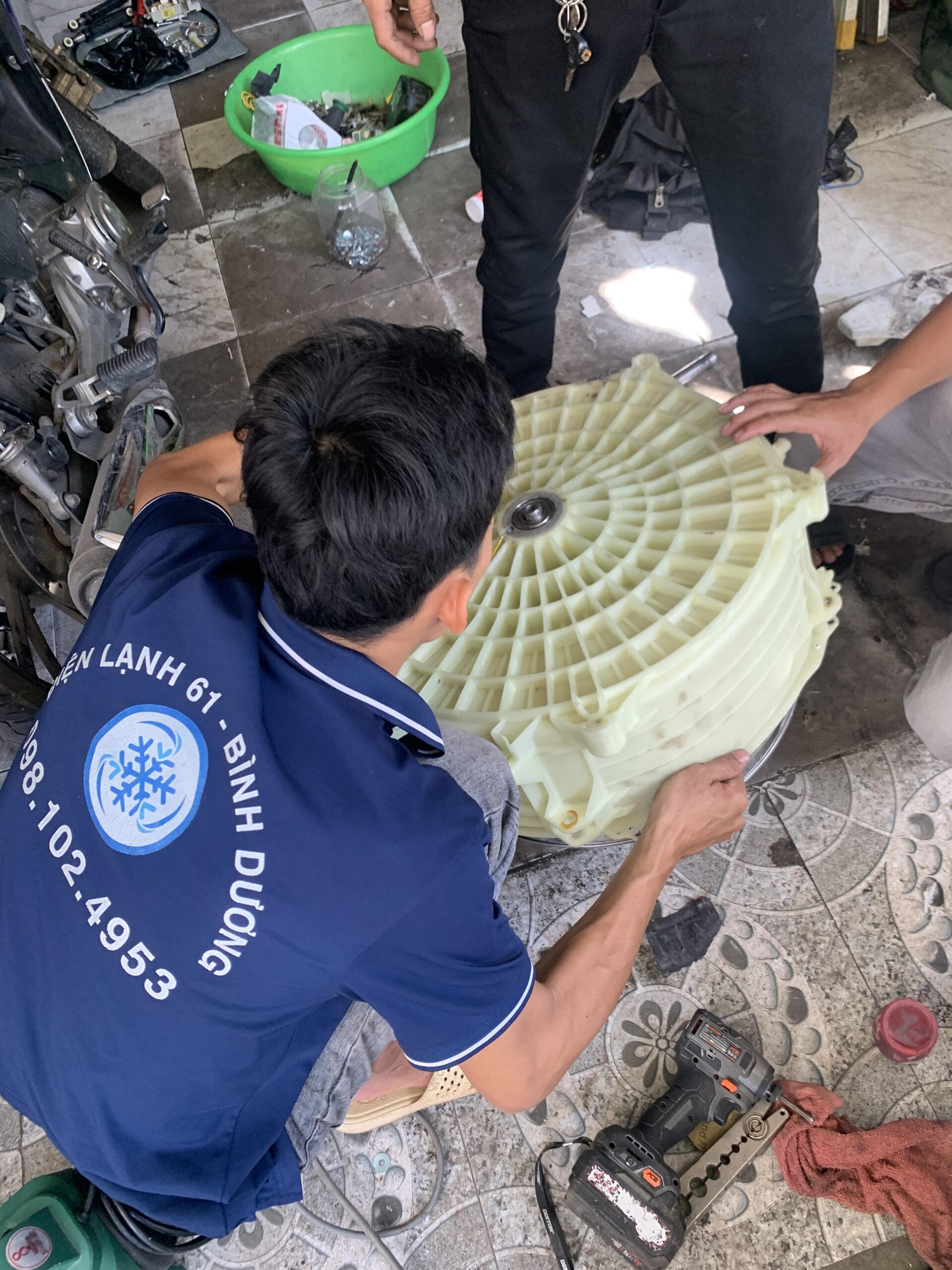 Thợ vệ sinh máy giặt Thuận An của Điện Lạnh 61 đang tháo rời lồng giặt.