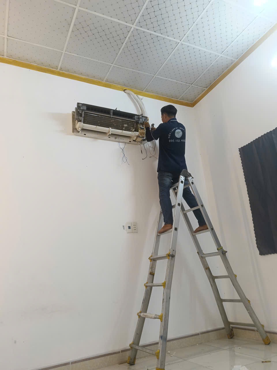 Thợ vệ sinh máy lạnh Dĩ An của Điện Lạnh 61 đang tháo mặt nạ dàn lạnh tại nhà khách hàng.