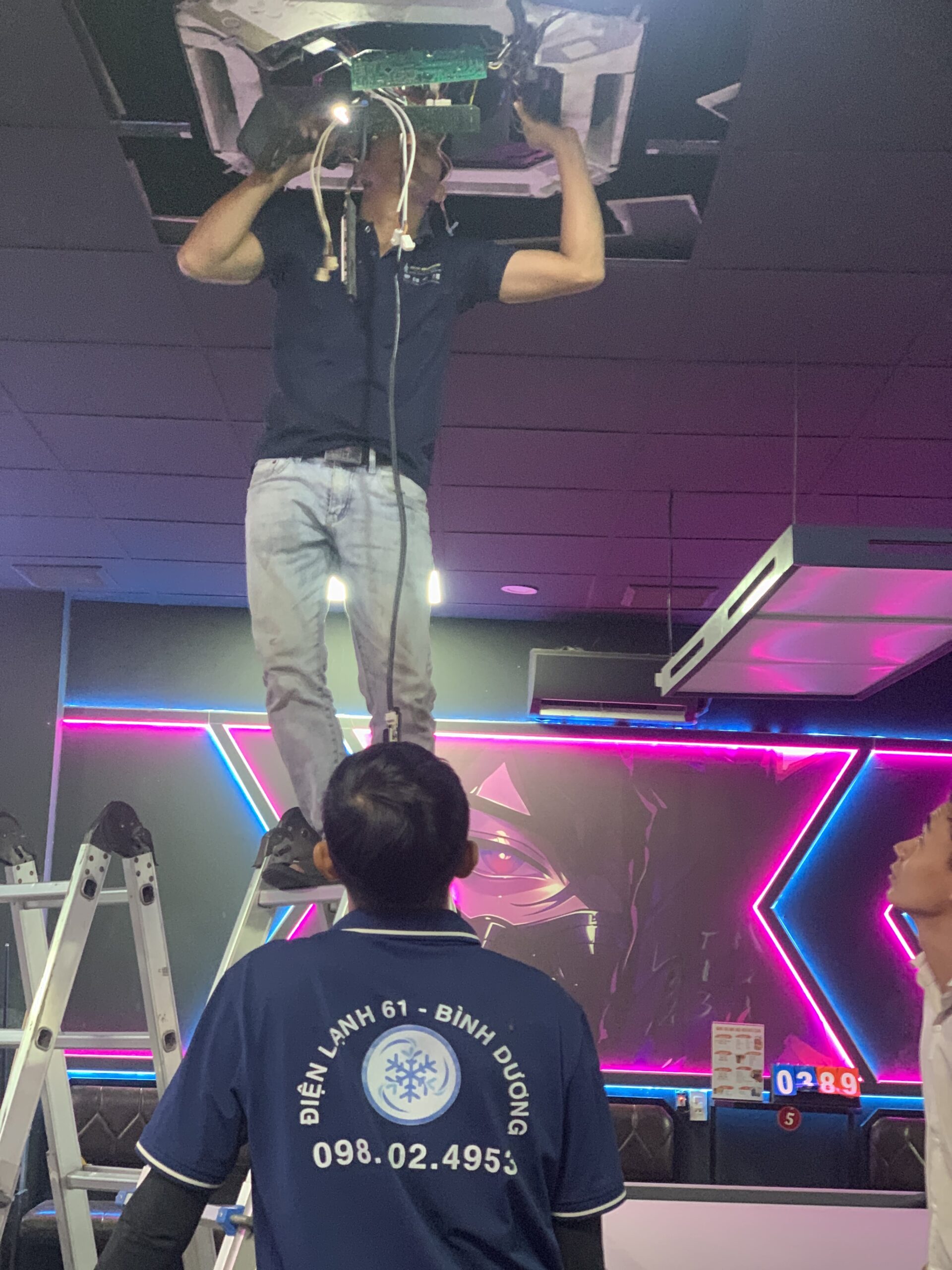 tho-dien-lanh-61-tien-hanh-nhot-gas-may-lanh-an-toan-truoc-khi-thao-do-tai-di-an Kỹ thuật viên cẩn thận tháo mặt nạ và gỡ dàn lạnh điều hòa không làm xước sơn tường.