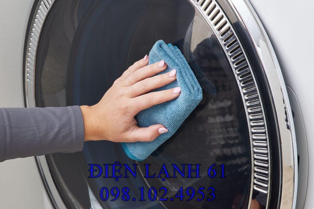 Người dùng lau vỏ máy giặt bằng khăn ẩm pha xà phòng Người dùng lau vỏ máy giặt bằng khăn ẩm pha xà phòng