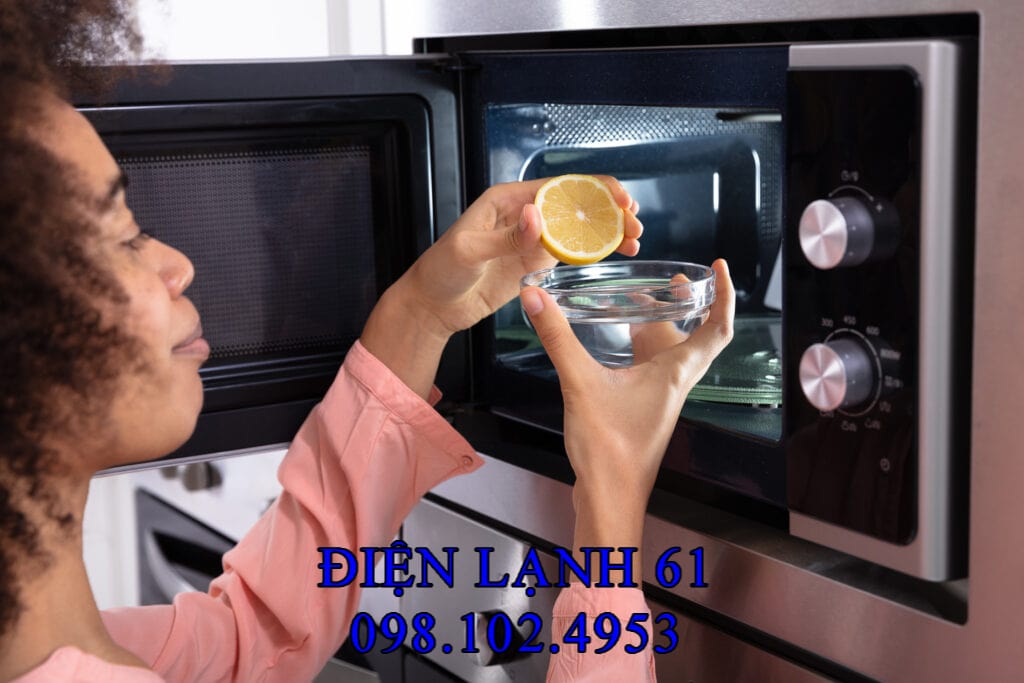 Cốc thủy tinh chứa nước và lát chanh sẵn sàng cho bước xông hơi vệ sinh lò vi sóng