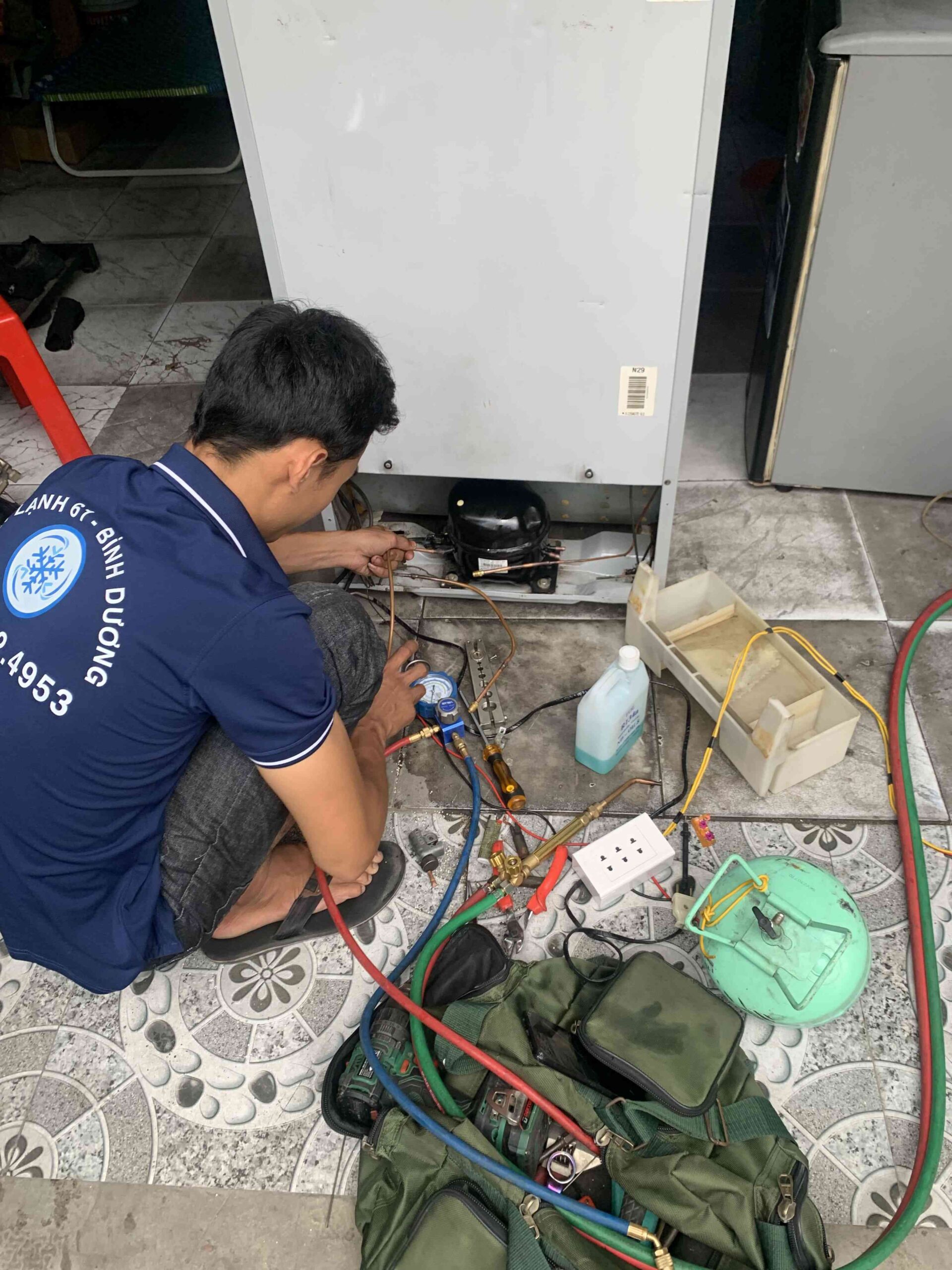 Kỹ thuật viên điện lạnh kiểm tra tủ lạnh để sửa chữa tại Lái Thiêu