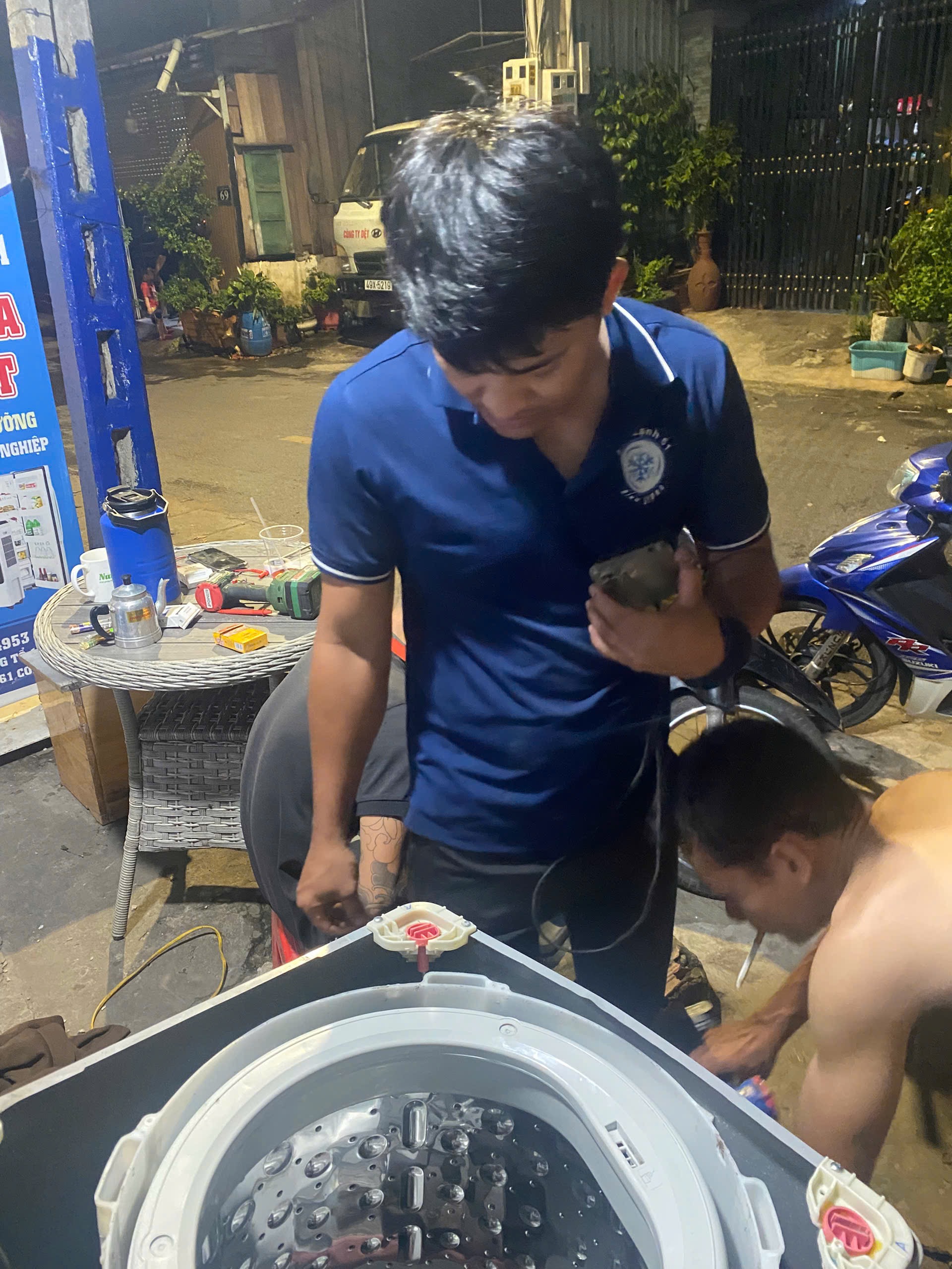 Kỹ thuật viên nhấc lồng inox máy giặt ra khỏi vỏ để xịt rửa tại nhà khách ở Đông Hòa.