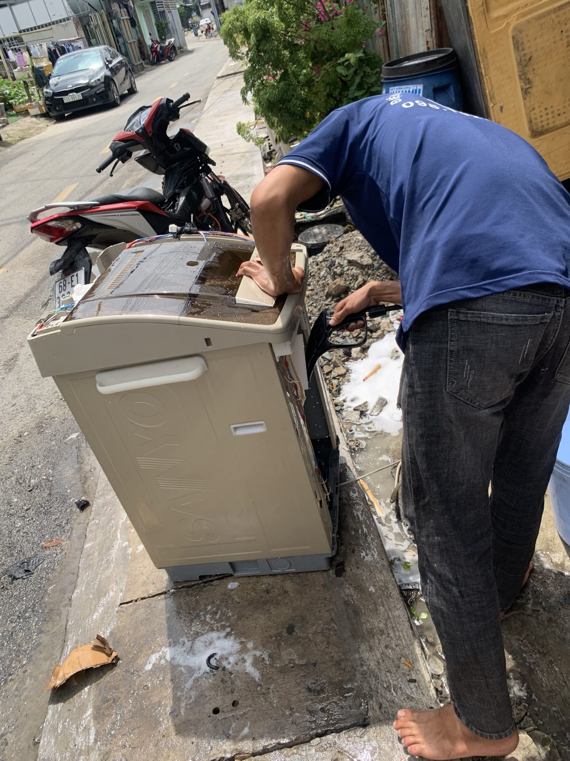 Kỹ thuật viên đang thực hiện sửa bo mạch máy giặt tại nhà khách hàng ở Đông Hòa