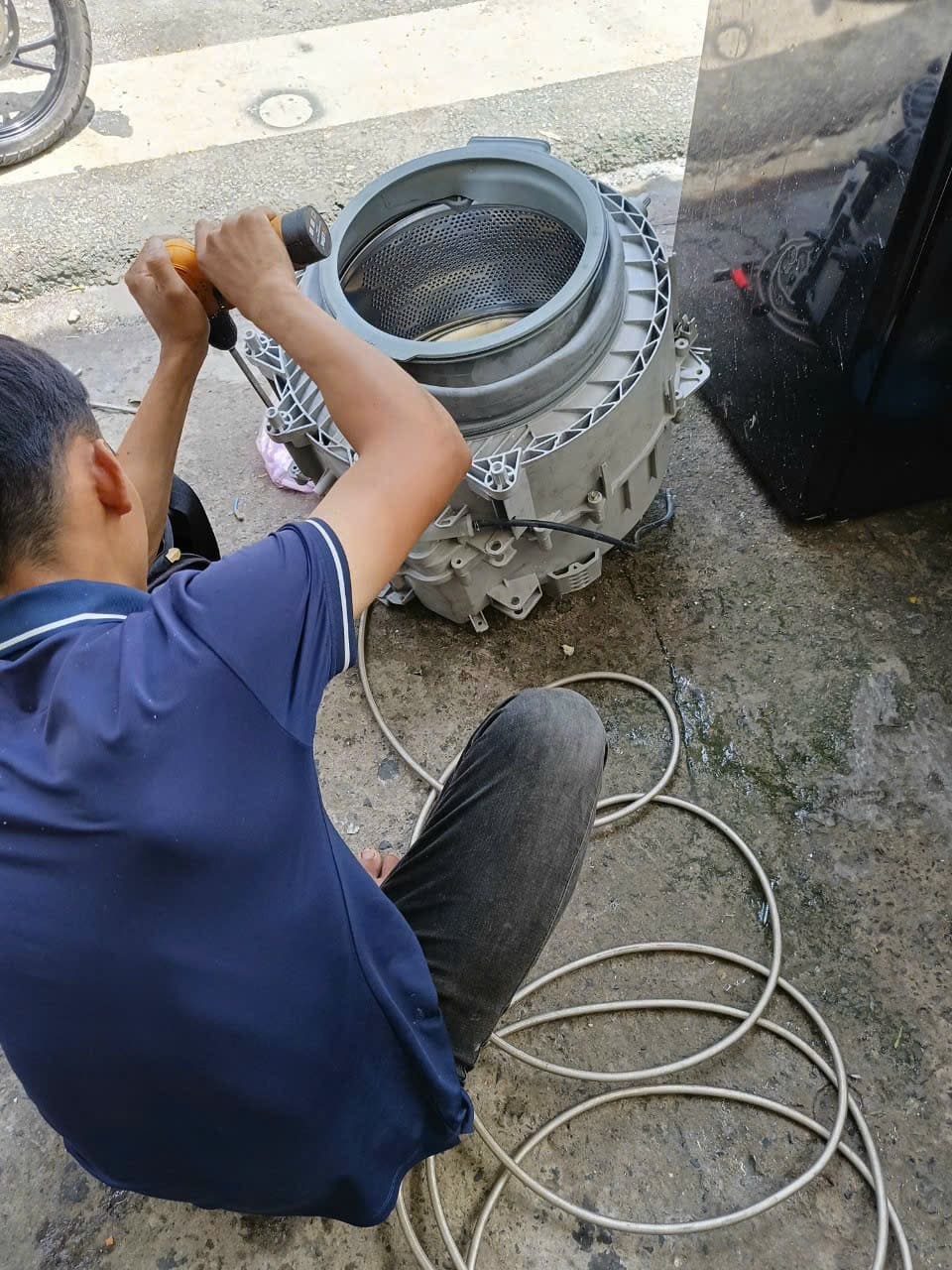 Thợ kỹ thuật đang tháo rời lồng máy giặt cửa ngang Electrolux để vệ sinh