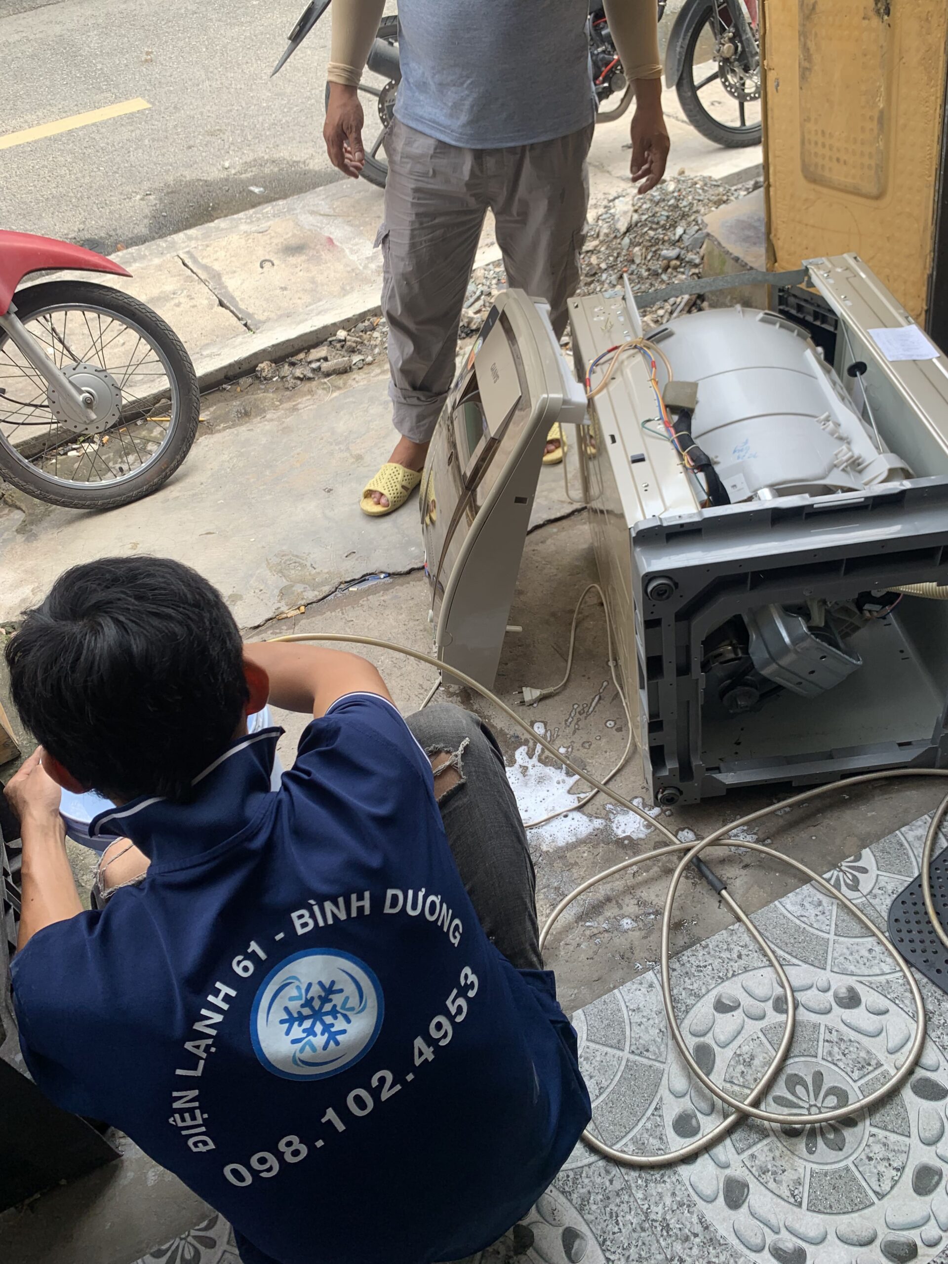 Kỹ thuật viên tháo rời lồng giặt để vệ sinh sâu bên trong.