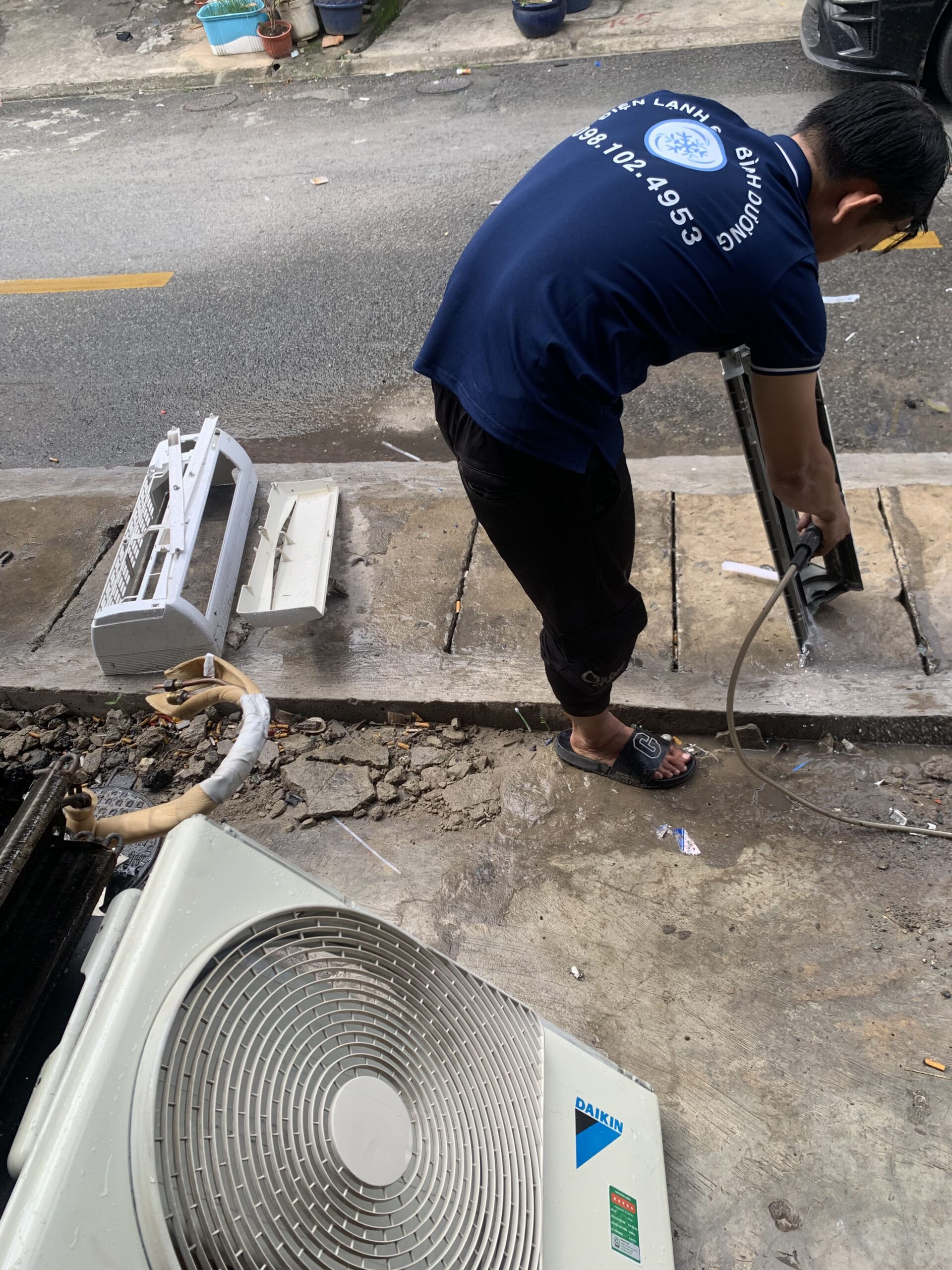 Tháo lưới lọc bụi dàn lạnh và rửa sạch dưới vòi nước tại phường An Phú
