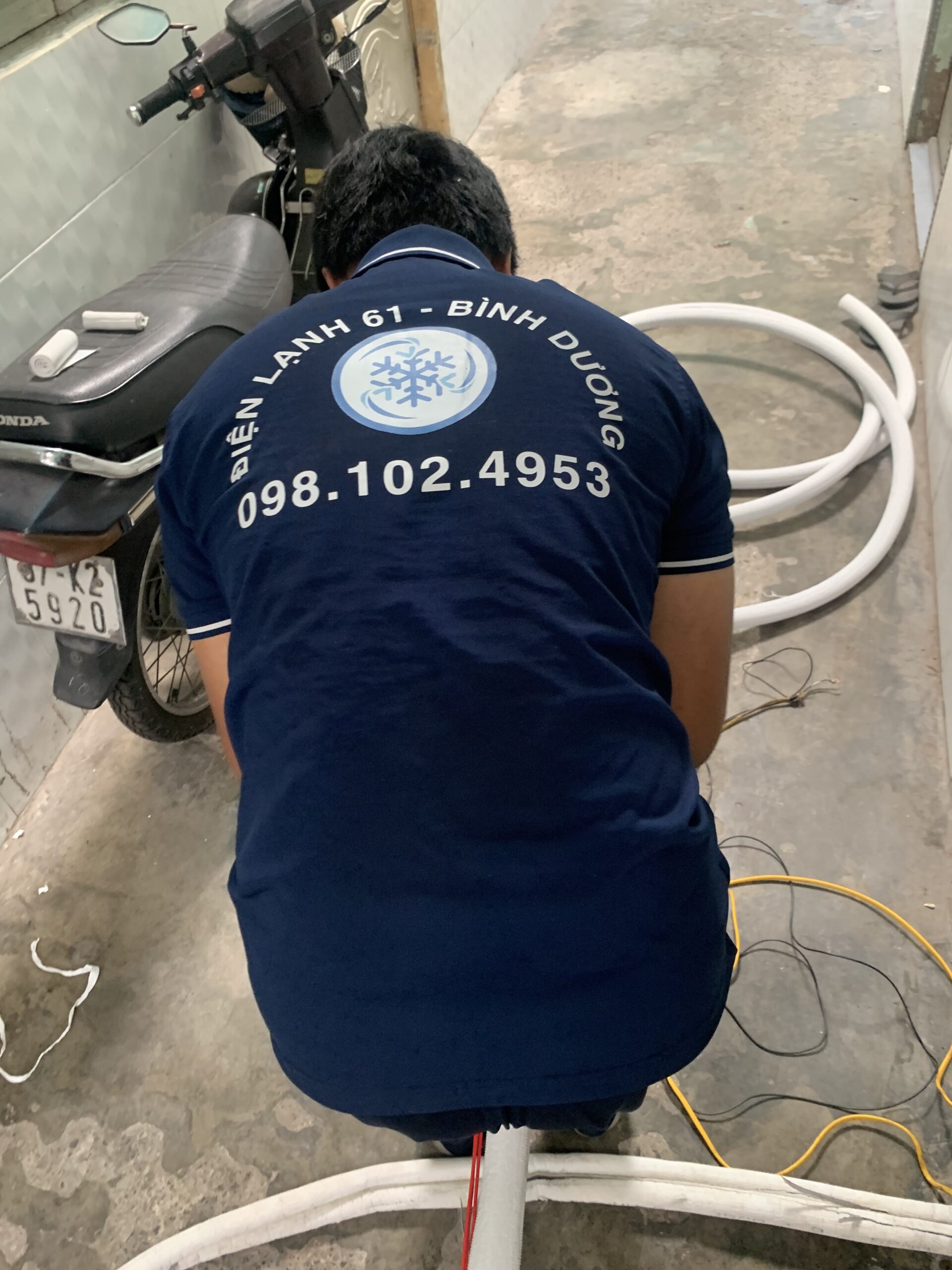 Thợ đang đi ống đồng và đấu nối dây điện cho máy lạnh tại một văn phòng ở Phú Lợi.