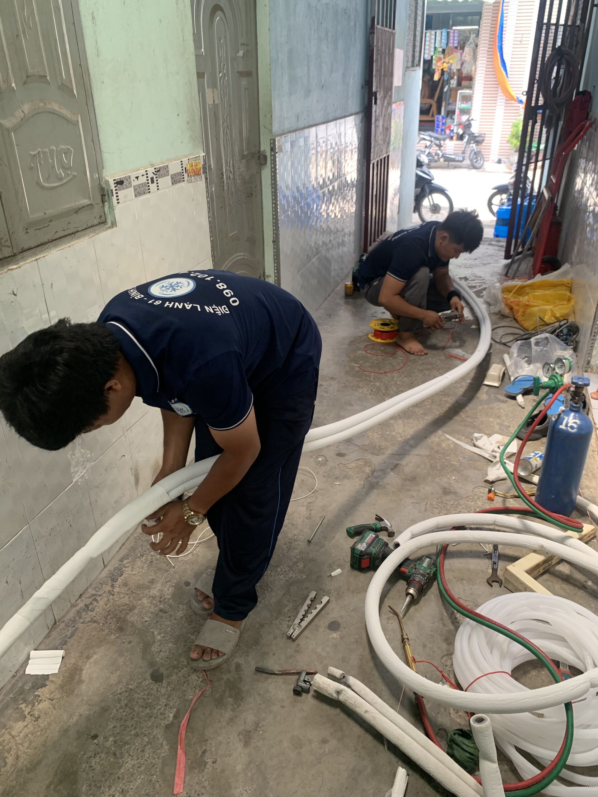 Thợ đang đi ống đồng và lắp đặt máy lạnh cho một quán cà phê tại Linh Xuân