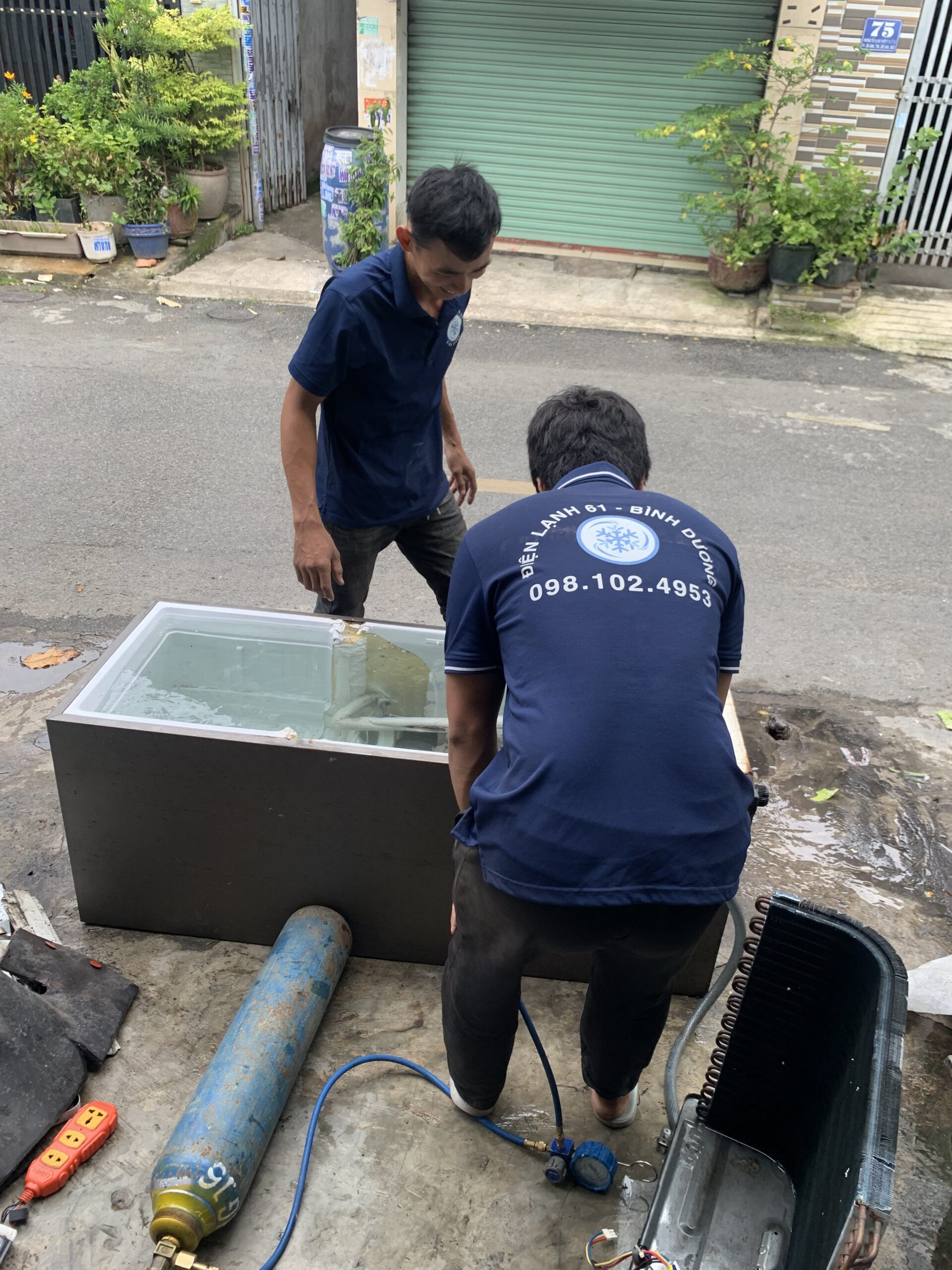 Thợ đang dùng đồng hồ đo gas để kiểm tra và sửa máy lạnh tại một gia đình ở Phú Lợi