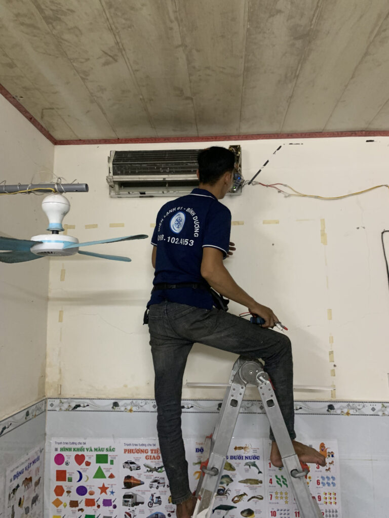 Thợ vệ sinh máy lạnh Bình Hòa của Điện Lạnh 61 đang tháo ốp nhựa mặt nạ dàn lạnh.