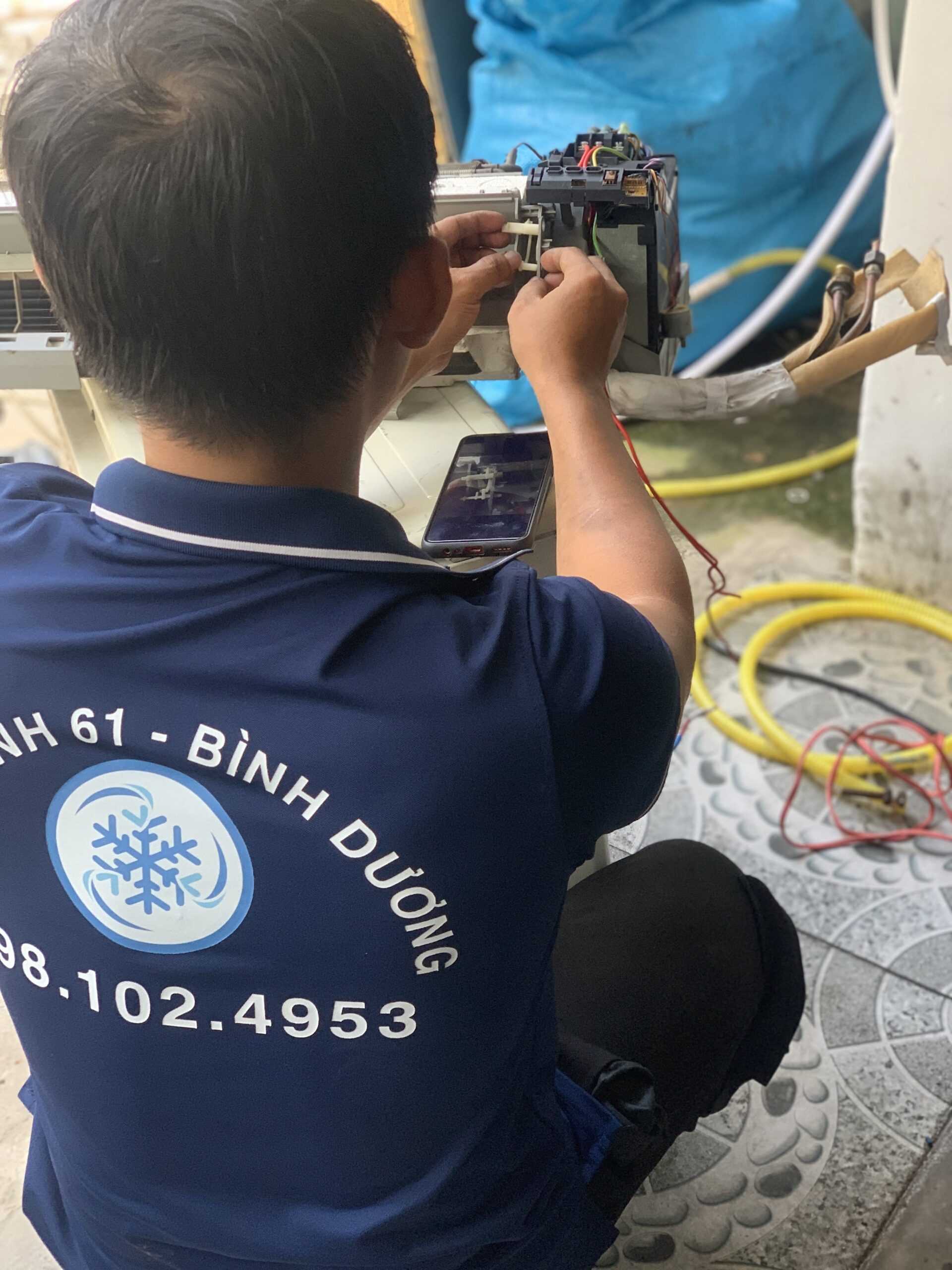 Kỹ thuật viên đang dùng đồng hồ đo để kiểm tra gas miễn phí sau khi bảo dưỡng máy lạnh