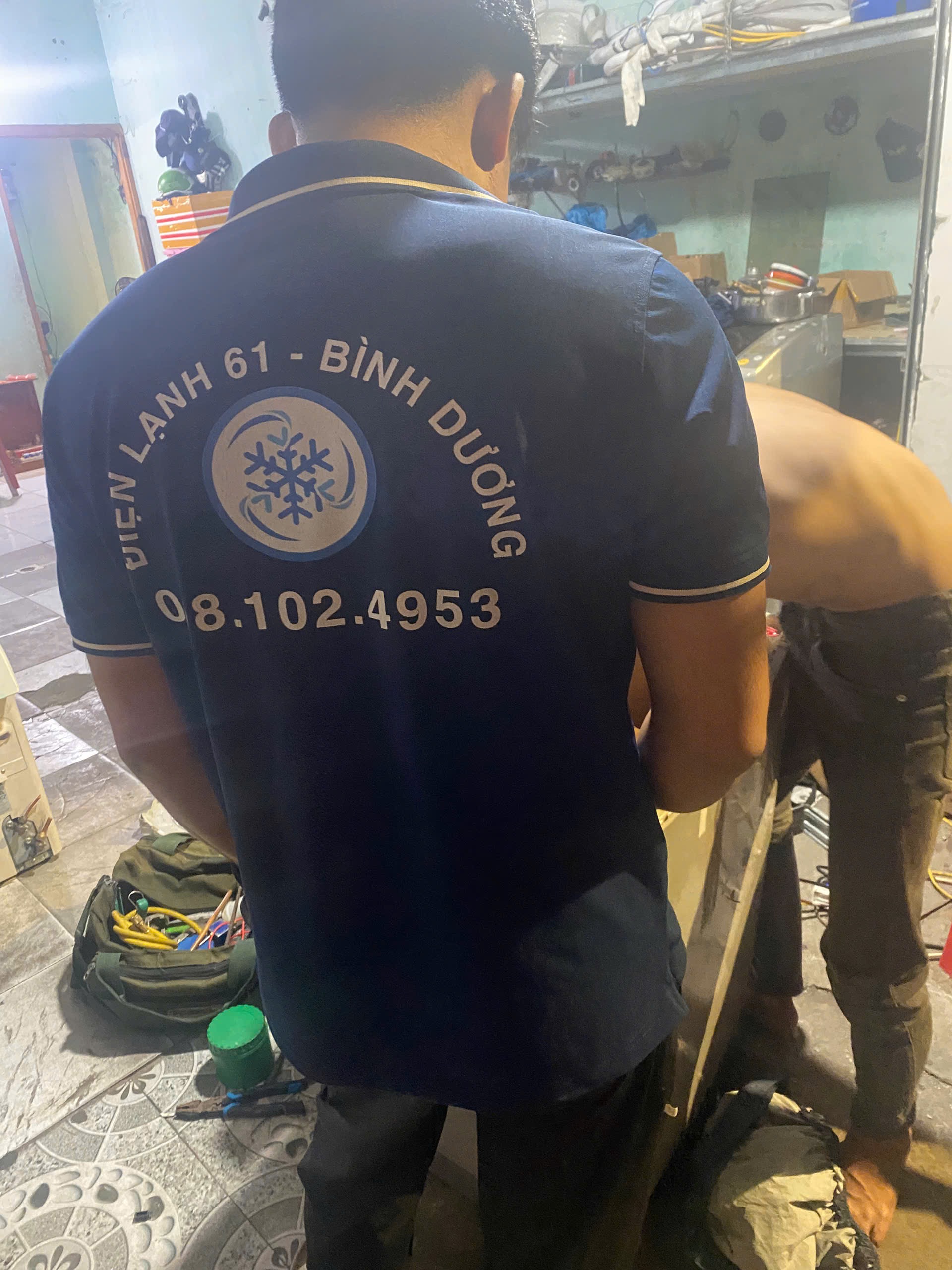 Kỹ thuật viên của Điện Lạnh 61 với đồng phục và dụng cụ đang sửa máy giặt cho khách hàng tại Dĩ An, Bình Dương.