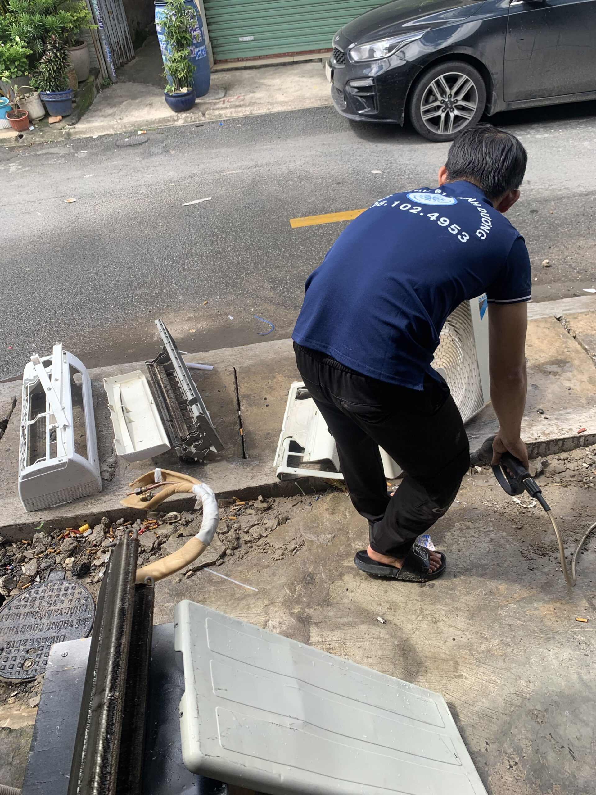 thợ đang dùng bạt che và máy bơm cao áp để vệ sinh dàn lạnh chuyên nghiệp