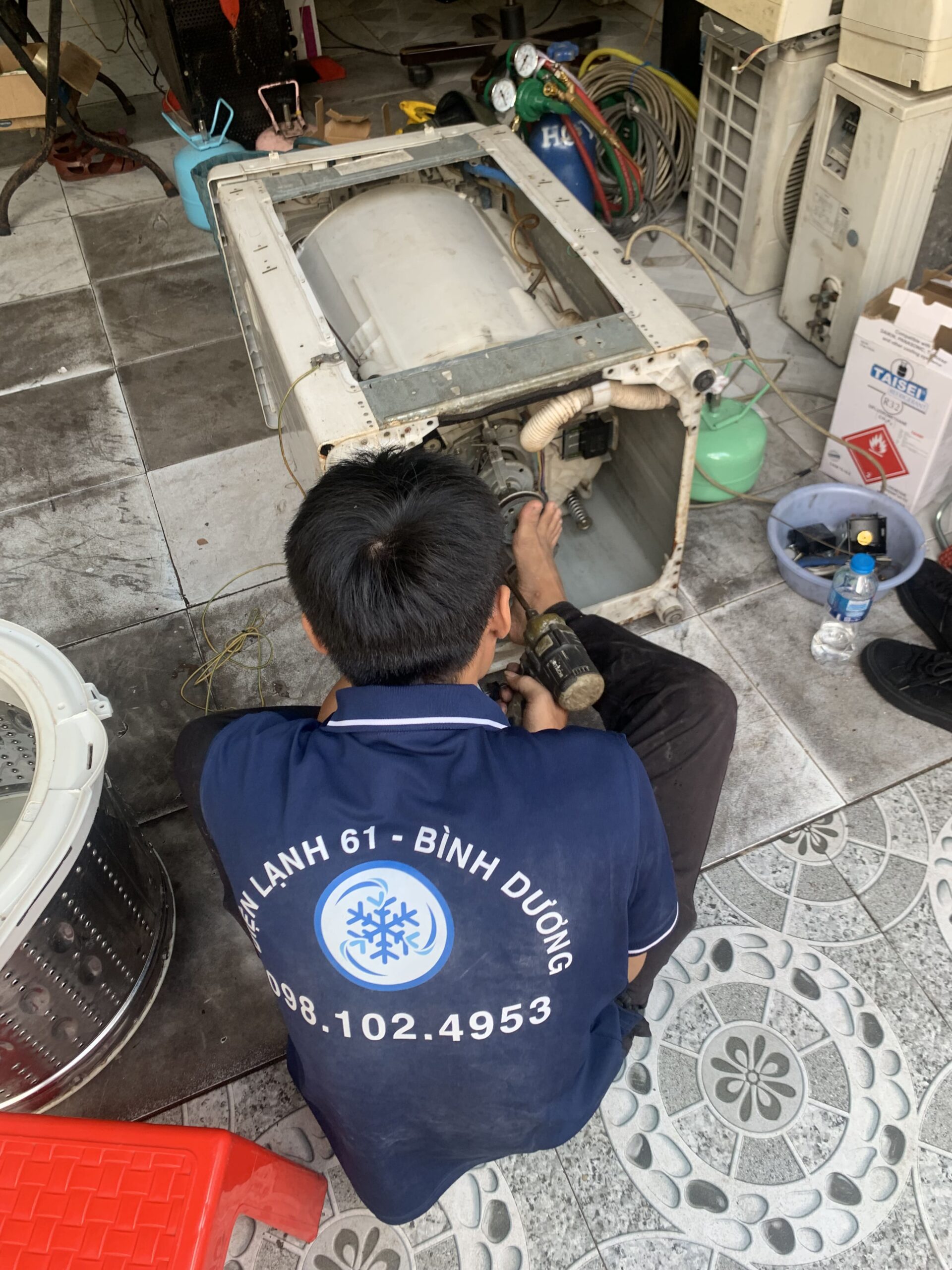 Thợ sửa máy giặt tại nhà Linh Xuân đang kiểm tra máy