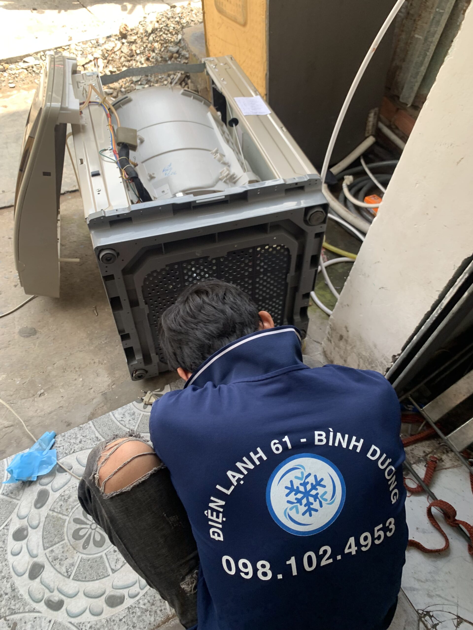 Kỹ thuật viên đang vệ sinh lồng giặt định kỳ chuyên nghiệp để tránh lỗi.