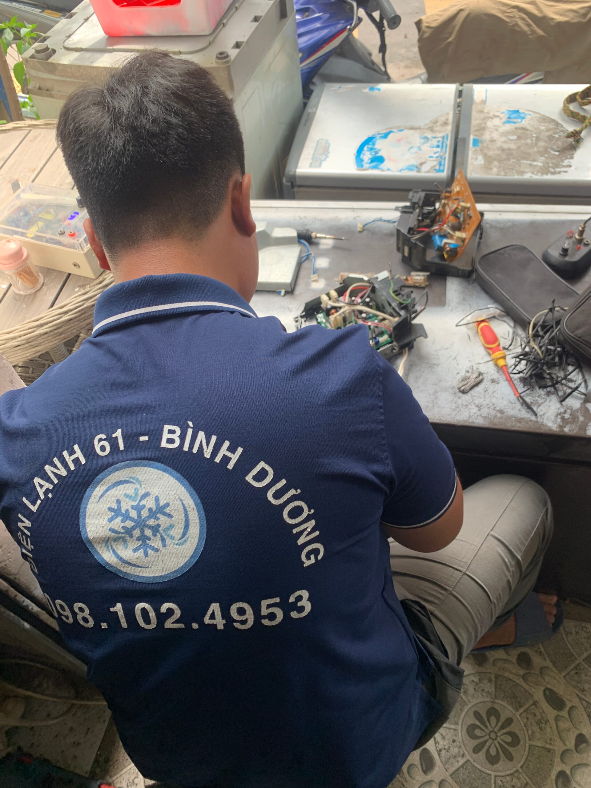 Kỹ thuật viên Điện Lạnh 61 đang dùng đồng hồ VOM đo bo mạch máy lạnh tại nhà khách.