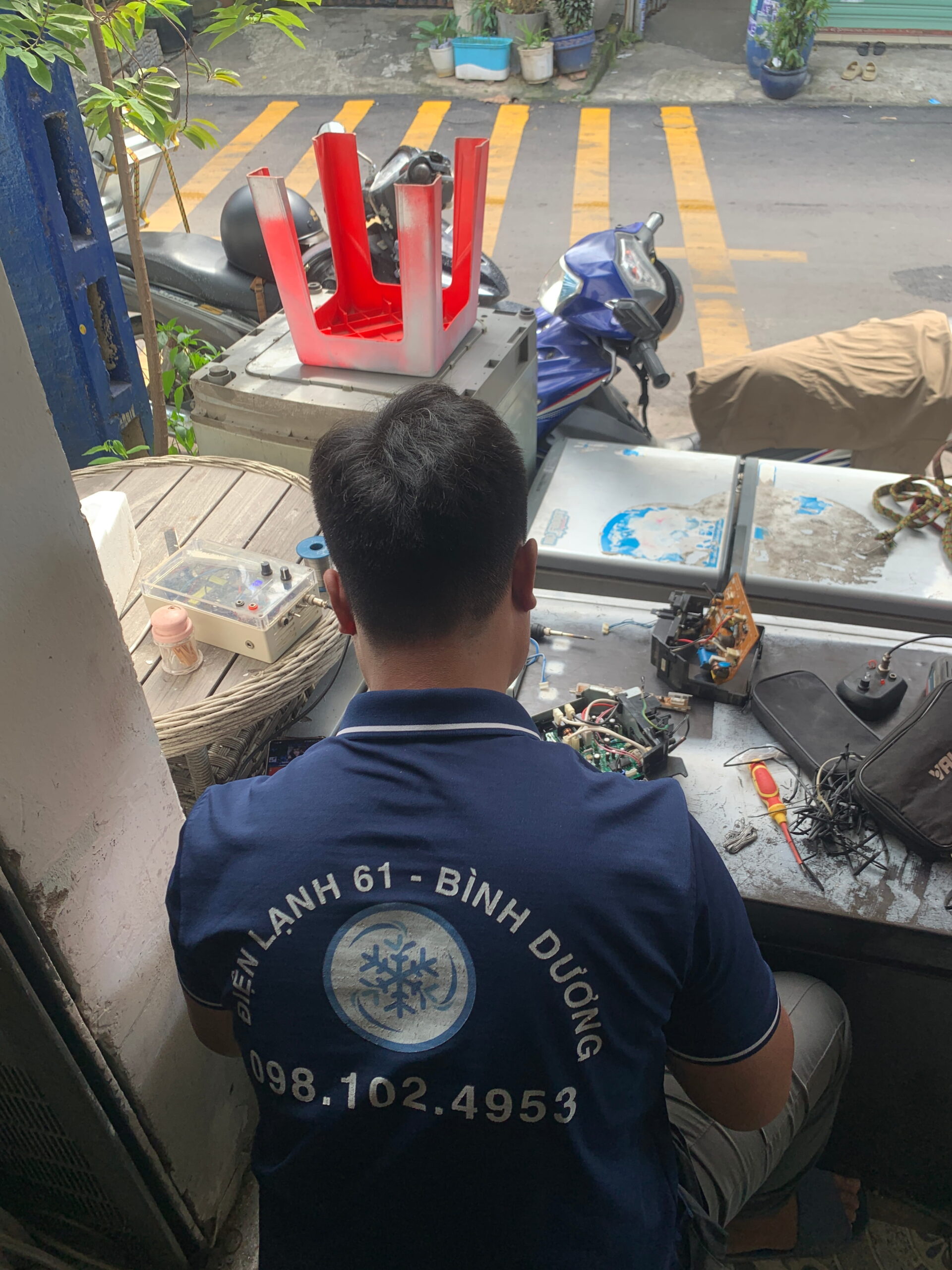 Kỹ thuật viên đang cặm cụi hàn linh kiện tại phòng kỹ thuật của Điện Lạnh 61 ở Dĩ An
