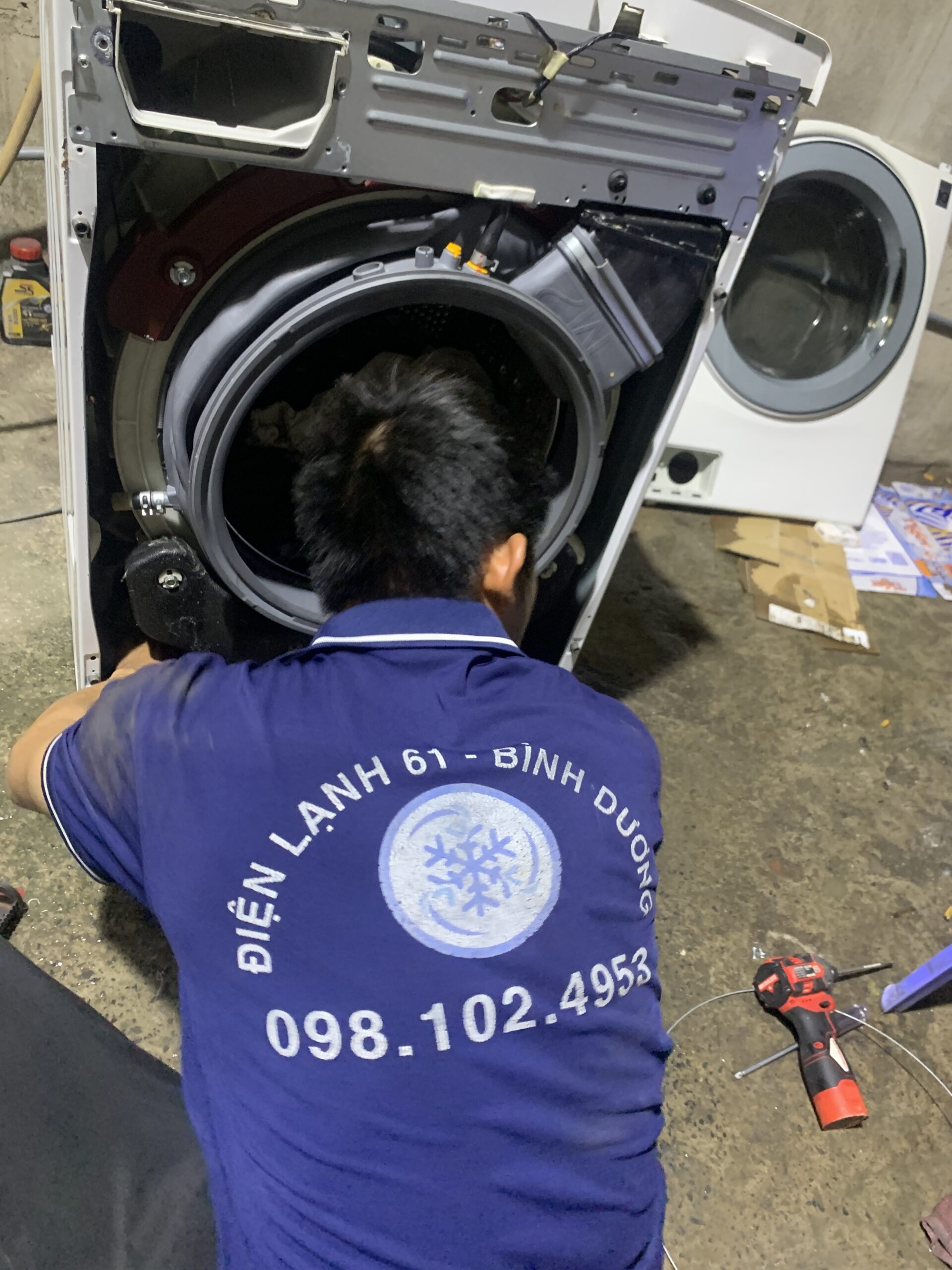 Thợ chuyên môn đang hướng dẫn kiểm tra và test máy giặt cũ trước khi mua bán.